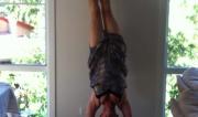 Martine Ford of Spirit Yoga practicing a handstand & knocking over a clock