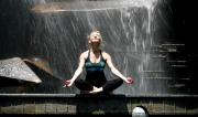 Martine Ford of Spirit Yoga meditating in front of water fall feature.
