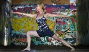 Martine Ford of Spirit Yoga in Warrier 2 Pose in front of colourful grafitti.