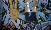 Martine Ford of Spirit Yoga in Tripod Headstand next to a peace mural