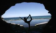 Martine Ford of Spirit Yoga in Dancers Pose in a cave near the ocean.