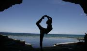 Martine Ford of Spirit Yoga in Full Dancers Pose in a cave near the ocean.